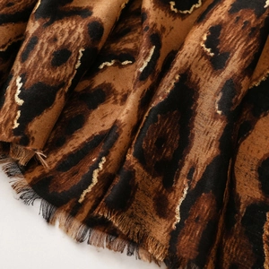Macro shot of leopard print scarf with gold thread details and fine fringe edges