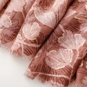 Close-up of pink shawl fabric featuring ginkgo leaf prints and frayed fringe edges