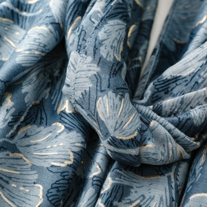 Detailed view of misty blue scarf featuring leaf prints and elegant gold foil edges