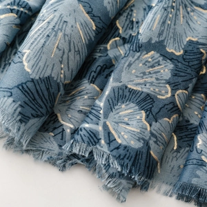 Close-up of blue cotton-linen scarf featuring gold foil gingko leaf prints and frayed edges