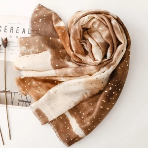 Detail of gradient tie-dye scarf with gold foil dots and frayed edges on white background