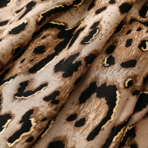 Detail of leopard print fabric with golden foil accents and soft frayed edges texture