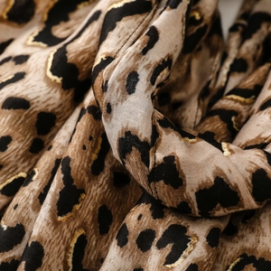 Macro detail of leopard print scarf fabric with gold foil accents and soft texture