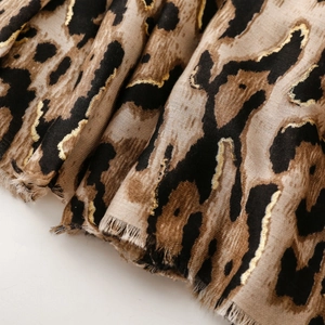 Detail of leopard print scarf with gold foil accents and soft frayed edge texture