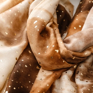 Detail of warm gradient cotton-linen scarf featuring gold foil heart and dot patterns