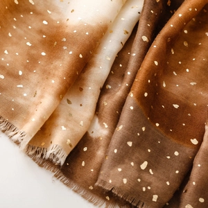 Close-up of gradient cotton scarf with gold foil accents and raw fringe edges