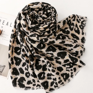 Detail of soft leopard print scarf with frayed edges and golden shimmer accents