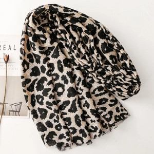 Detail of leopard print scarf with gold foil accents and soft frayed edges on white surface