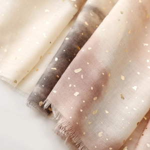 Macro detail of gradient cotton linen scarf with gold foil dots and frayed edges