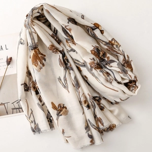Detailed view of floral printed cotton linen scarf with soft fringe edges and golden pattern