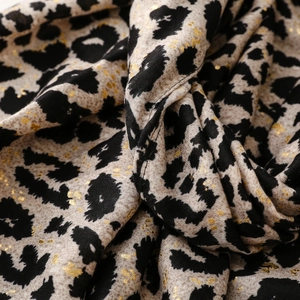 Detailed close-up of leopard print fabric with metallic gold foil and stitched edges
