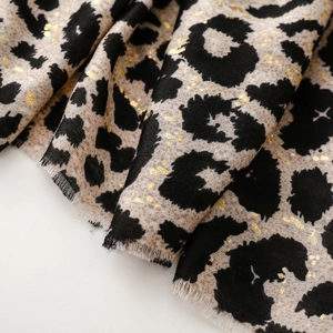 Detailed macro view of soft linen-cotton scarf featuring gold foil leopard print and frayed edges