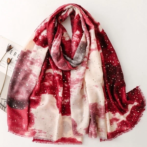 Detail of red tie-dye scarf with gold foil dots and delicate fringe on white background