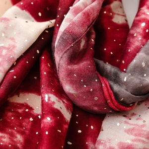 Macro view of cotton linen scarf featuring gold foil dots and red tie-dye gradient texture