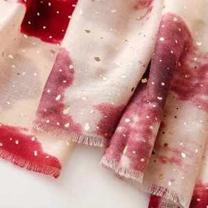 Detail of red tie-dye pattern with gold foil dots on soft cotton-linen scarf with fringes