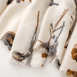 Detail of off-white scarf with gold foil floral print and frayed fringe edges