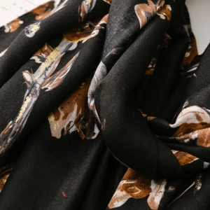 Close-up of black cotton-linen scarf featuring gold floral patterns and twill weave texture