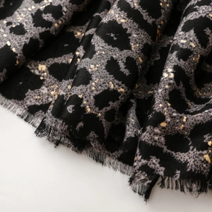 Macro detail of leopard print scarf with gold foil accents and soft fringed edges