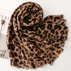 Detail of leopard print scarf with gold foil accents and soft fringed edges on white background