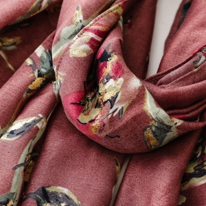 Close-up of luxury dark red scarf with metallic gold floral patterns and fine fabric texture