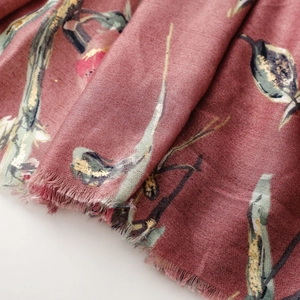Detail of dusty rose scarf with golden floral prints and delicate fringed edges