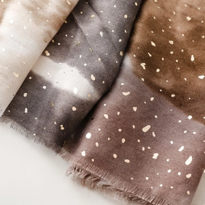 Macro detail of gradient satin scarves with gold foil dots and delicate fringe edges
