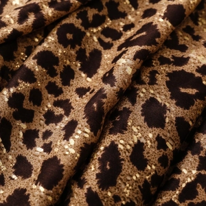 Macro view of leopard print fabric with metallic gold accents and soft draped texture