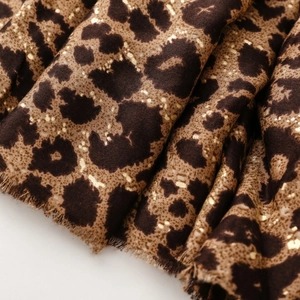 Detailed macro view of leopard print fabric with luxury gold foil spots and frayed edges