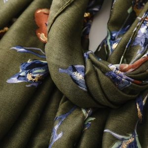 Detailed close-up of olive green satin shawl featuring floral prints and gold foil accents