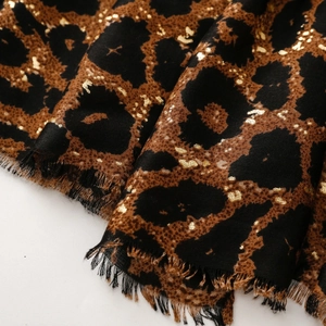 Detail of leopard print scarf featuring gold foil accents and delicate fringe edges