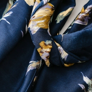 Macro detail of navy floral scarf with metallic gold foil accents and soft fabric texture
