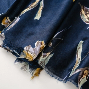 Close-up of navy blue floral cotton-linen shawl with golden foil print and frayed edges