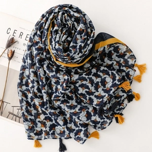 Detailed view of bohemian cotton-linen scarf with ginkgo leaf print and vibrant yellow tassels