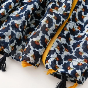 Macro shot of navy blue scarf featuring white floral prints and yellow fringed tassels
