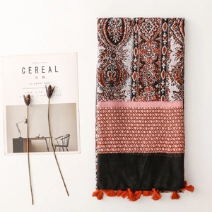 Close-up of Bohemian cotton linen shawl with Paisley patterns and orange tassels