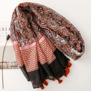 Detail of ethnic print scarf with complex geometric patterns and red tassel accents