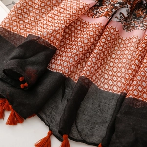 Close-up of bohemian linen scarf showing paisley diamond prints and orange tassels