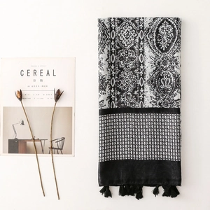 Detail of bohemian scarf with geometric patterns and black tassels on a minimalist setting