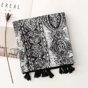 Flat lay of bohemian paisley print scarf with black tassels on minimalist background
