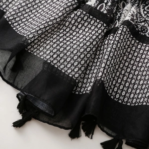 Macro detail of bohemian black and white paisley and geometric print scarf with tassels