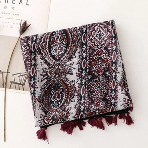 Macro detail of Bohemian paisley print scarf with deep red tassels and cotton-linen texture