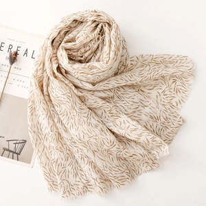 Detail of soft cream cotton scarf with metallic gold feather print and frayed edges
