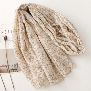 Detailed texture of beige cotton linen shawl with elegant gold foil leaf patterns