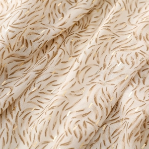 Detail of soft cotton-linen scarf featuring golden geometric prints and warm ivory texture