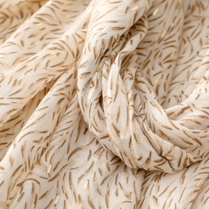 Detail of soft beige scarf featuring elegant gold foil patterns and abstract brushstrokes