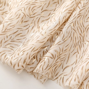 Detail of soft off-white cotton linen scarf with gold foil accents and frayed edges