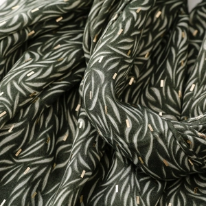Close-up of dark green scarf showing leaf patterns and golden rectangular accents