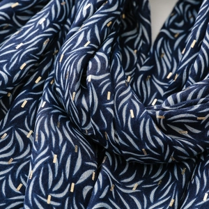 Macro shot of navy blue scarf fabric with gold foil rectangles and leaf pattern