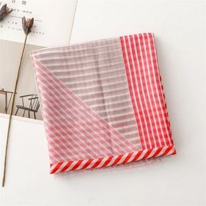 Detail of red striped cotton-linen scarf with raw fringe edges on white background