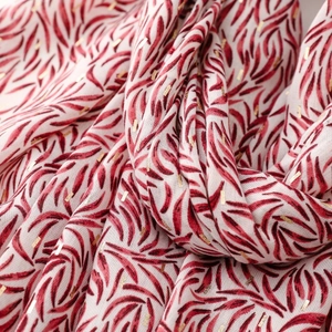 Detail of white cotton linen scarf with red leaf prints and gold foil rectangular accents